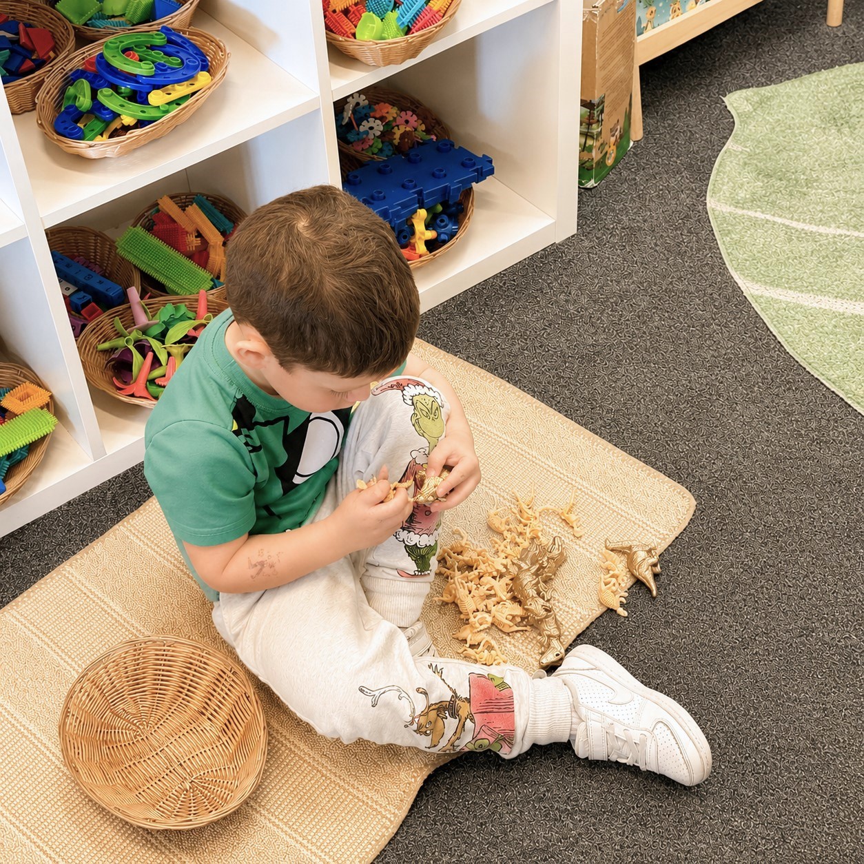 Child engaged in hands-on dinosaur play, developing creativity, fine motor skills, and independent learning in a nurturing early childhood classroom.