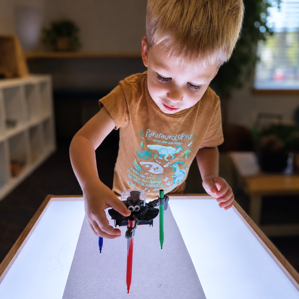Child exploring a light table drawing activity with a hands-on STEM tool at Edina Daycare, supporting problem-solving, creativity, and kindergarten readiness through active learning.