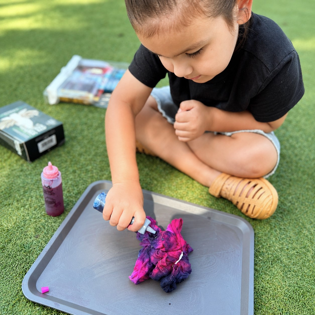 Child independently exploring a hands-on outdoor sensory activity with tools and materials at Edina Daycare, building problem-solving skills, focus, and confidence through self-directed play.