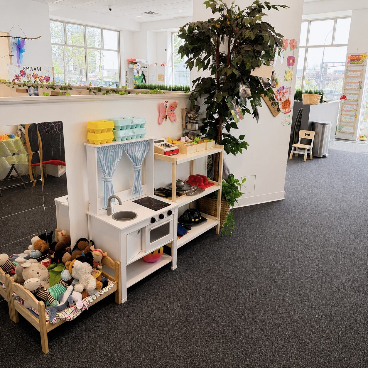 Well-organized toddler classroom featuring low, accessible shelves and a child-height play kitchen with neatly arranged materials, supporting independent choice-making, self-help skills, and confidence through self-directed play at Edina Daycare.