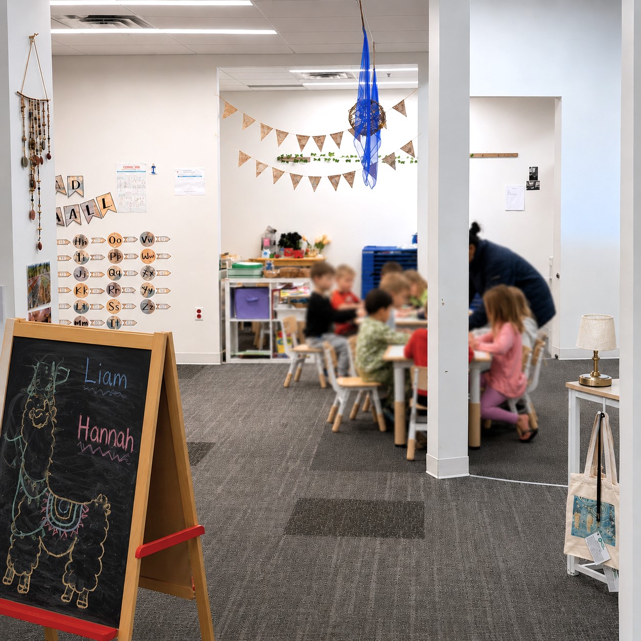 Spacious classroom at Edina Daycare West Campus with open learning areas, a chalkboard easel, and children engaged at tables, highlighting an organized, engaging environment for exploration and collaboration.